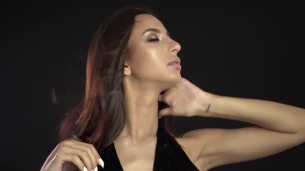 Модная брюнетка стоит на фоне черной стены в студии — стоковое видео