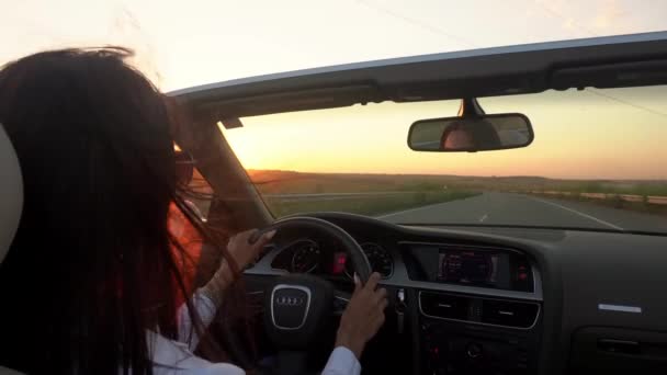 Jonge vrouw rijdt cabriolet en zingt. De wind blaast haar haar. — Stockvideo