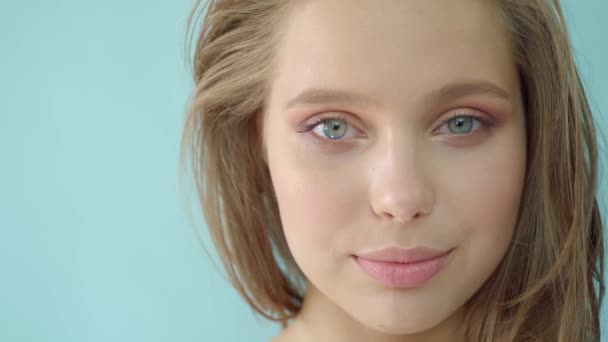 Ragazza in studio su un bluebackground.Advertising, prodotti per capelli, salone di bellezza, cosmetici, abbigliamento. Moda, boutique. Rosa . — Video Stock