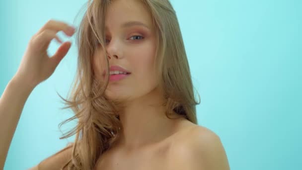 Portret van sensuele mooie jonge vrouw met blauw grijze ogen kijken naar camera in een licht blauwe achtergrond. — Stockvideo