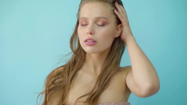 Portrait of sensual beautiful young woman with blue grey eyes looking at camera in a light blue background. — Stock Video