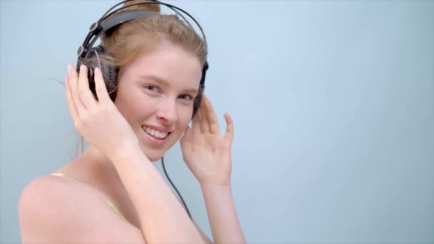 Щаслива красива дівчина-імбир посміхається і слухає музику в навушниках . — стокове відео
