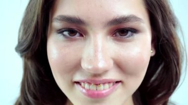 Genç kadın beyaz arka planda gözlerini aç. Stüdyoda kameraya bakan gülümseyen kıza yaklaş. Kadın doğası güzelliği