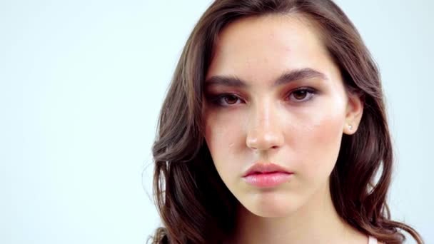 Mujer joven abrir los ojos sobre fondo blanco. Primer plano de chica sonriente mirando a la cámara en el estudio. Belleza naturaleza femenina — Vídeos de Stock