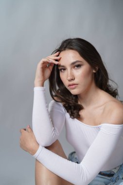 Genç kadın beyaz arka planda gözlerini aç. Stüdyoda kameraya bakan gülümseyen kıza yaklaş. Kadın doğası güzelliği