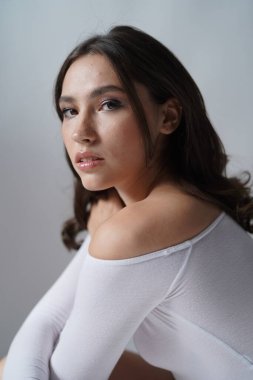 Genç kadın beyaz arka planda gözlerini aç. Stüdyoda kameraya bakan gülümseyen kıza yaklaş. Kadın doğası güzelliği