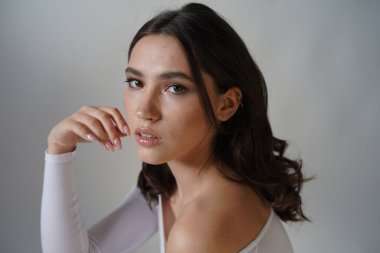 Genç kadın beyaz arka planda gözlerini aç. Stüdyoda kameraya bakan gülümseyen kıza yaklaş. Kadın doğası güzelliği