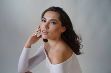 Genç kadın beyaz arka planda gözlerini aç. Stüdyoda kameraya bakan gülümseyen kıza yaklaş. Kadın doğası güzelliği