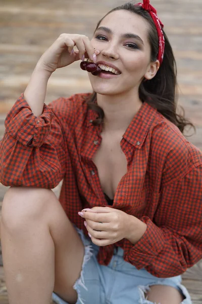 Kiraz yiyen güzel kadınların yakın plan portresi. Bir kadının ağzına nişan al. Açık havada.