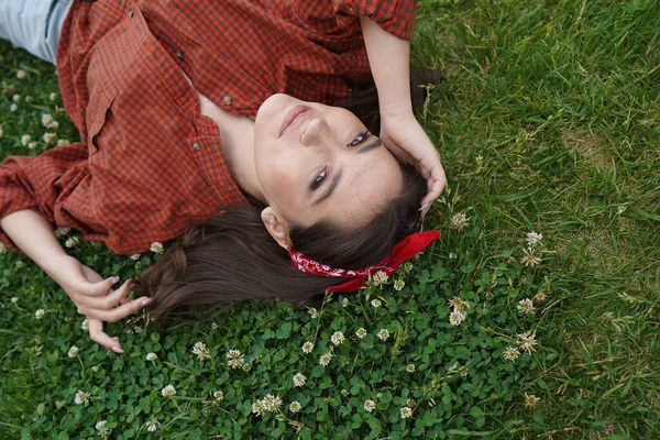 Een meisje ligt op haar rug op het gras — Stockfoto