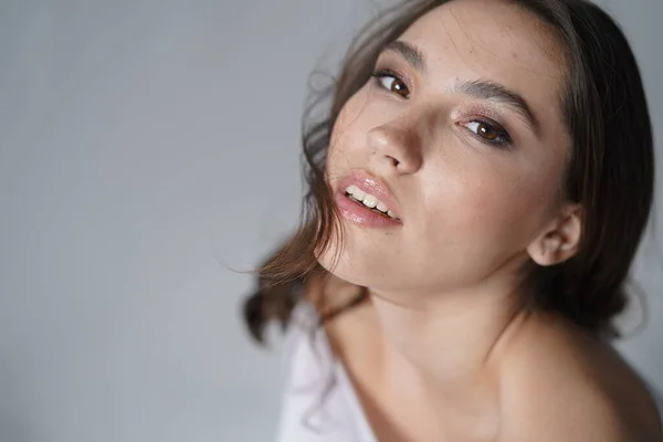 Mujer joven abrir los ojos sobre fondo blanco. Primer plano de chica sonriente mirando a la cámara en el estudio. Belleza naturaleza femenina —  Fotos de Stock