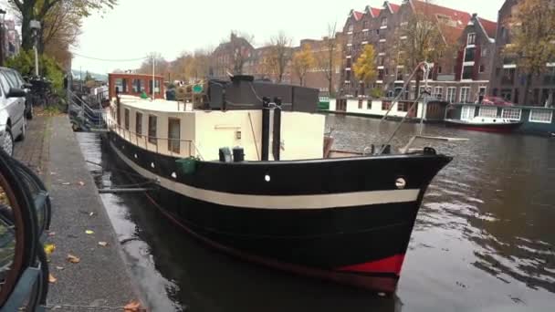 Ámsterdam, Países Bajos - 20 de noviembre de 2019: Ámsterdam ciudad con barcos en el canal. Casas flotantes, casas flotantes y barcos en los canales por los bancos — Vídeos de Stock