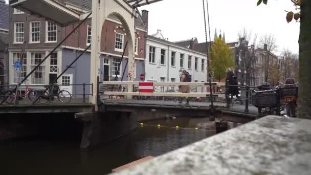 Ámsterdam, Países Bajos, noviembre de 2019. Gente en bicicleta y caminando en un puente sobre el canal en Amsterdam. — Vídeos de Stock