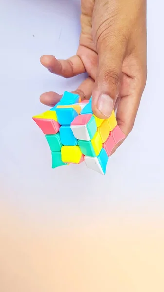 Business Concept and puzzle cubes of decision making process logical thinking. Logical tasks. Hand holding Box puzzle element on Blue - Orange paper background