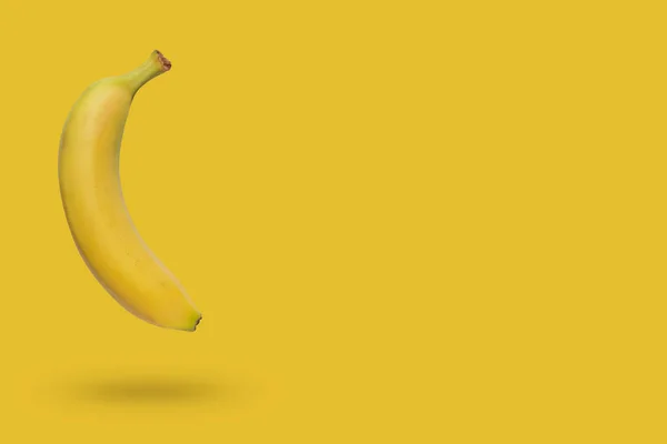 Banana isolada em fundo amarelo com uma sombra — Fotografia de Stock