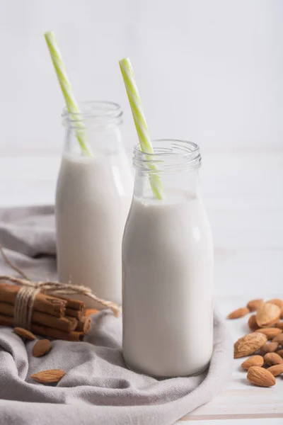 Latte di mandorla e cannella su un tavolo di legno bianco — Foto Stock