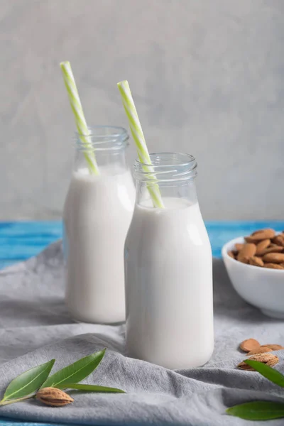 Latte di mandorla in due bottiglie sullo sfondo rustico di legno blu — Foto Stock