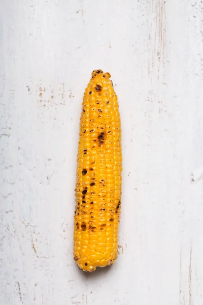 Único grelhado espigas de milho no fundo de madeira branca — Fotografia de Stock