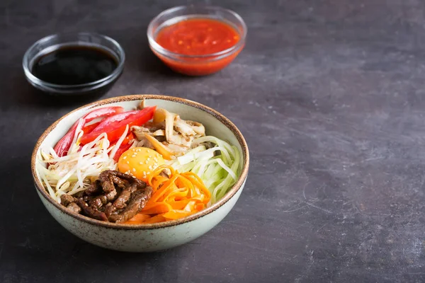 Traditionelles asiatisches Bibimbap-Gericht mit Reis und Gemüse auf dunklem Hintergrund mit Kopierraum — Stockfoto