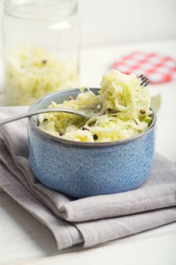 Ahşap bir masa üzerinde mavi bir kasede lahana turşusu