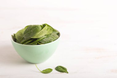 Beyaz masanın üzerine bir kase taze mini ıspanak yıkanır