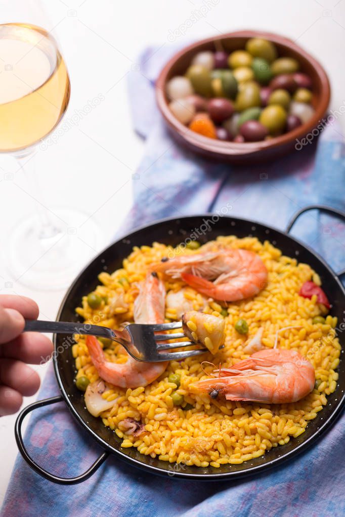 National Spanish Valencian rice dish paella tinted with saffron. Prepared with olive oil, seafood, vegetables and chicken