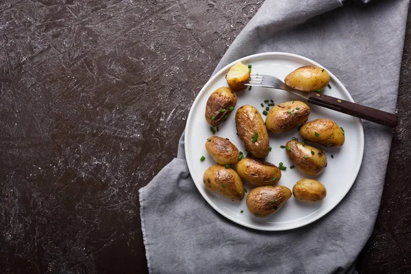烤小土豆与绿色洋葱在白色的盘子 水平方向与复制空间 黑暗的背景 — 图库照片