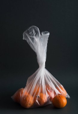 Meyveleri koyu arka plan üzerinde plastik torbalarda. Görüntü yapay gıda depolama torbaları kullanılarak zarar gösterir