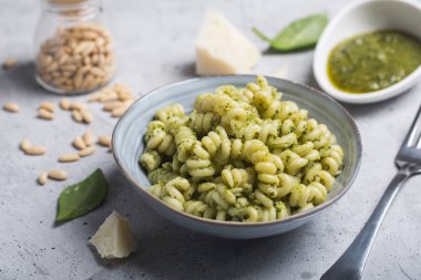 Gri beton zemin üzerine pesto soslu makarna düdük tabak