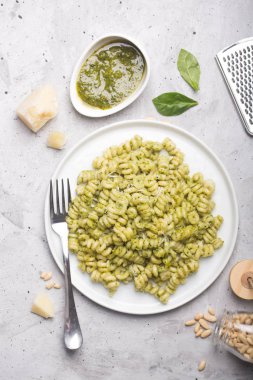 Gri beton zemin üzerine pesto soslu makarna düdük tabak