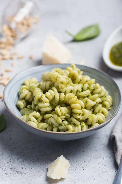 Plate of pasta fusilli with pesto sauce and parmesan cheese on gray concrete background — Stock Photo, Image