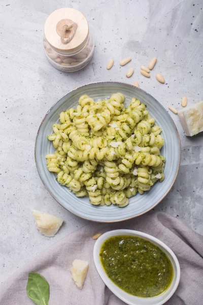 Plate of pasta fusilli with pesto sauce and parmesan cheese on gray concrete background — Stock Photo, Image
