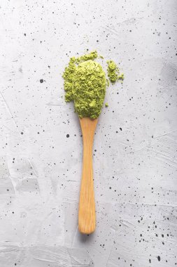 Beton yüzeyinde bir kaşık yeşil çay Matcha. Çekim yakın