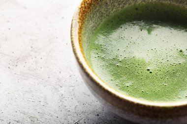 Beton yüzeyde bir kase yeşil çay Matcha üst görünümü. Çekim yakın