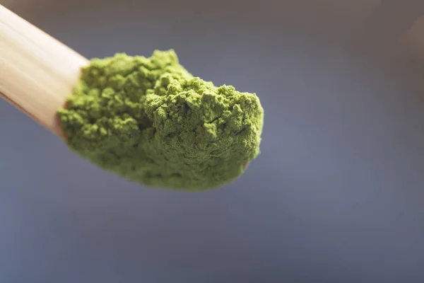 Green tea matcha in a spoon on a dark surface. Close up shot