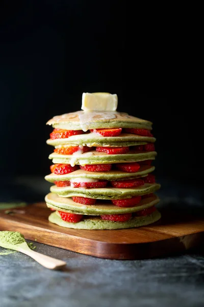 Homemade matcha Pancakes with strawberries and Butter. Ready for breakfast. Dark background
