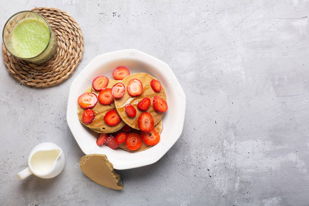 Homemade Pancakes with strawberries and Butter. Ready for breakfast. Matcha latte on the table, flat lay, top view