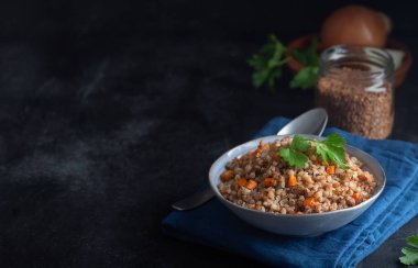 Koyu bir arka plan üzerinde bir kapta havuç, maydanoz ve tereyağı ile Haşlanmış karabuğday tahıl. Kopya alanı ile koyu arka plan üzerinde Geleneksel Rus çanak