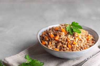 Koyu bir arka plan üzerinde bir kapta havuç, maydanoz ve tereyağı ile Haşlanmış karabuğday tahıl. Kopya alanı ile gri arka plan üzerinde Geleneksel Rus çanak