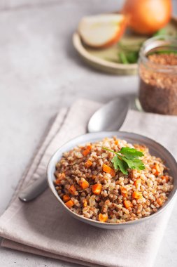 Gri bir arka plan üzerinde bir kase havuç, maydanoz ve tereyağı ile Haşlanmış karabuğday tahıl. Kopya alanı ile gri arka plan üzerinde Geleneksel Rus çanak