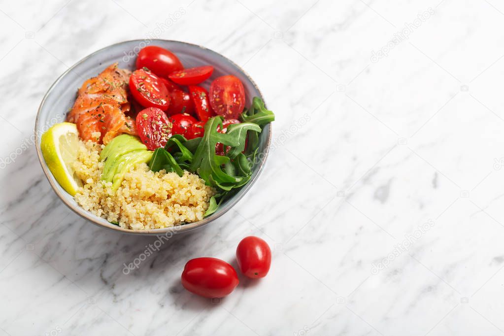 Dietary bowl salad with quinoa, salmon and vegetables, such as tomatoes and arugula. Fresh vitamin organic salad.