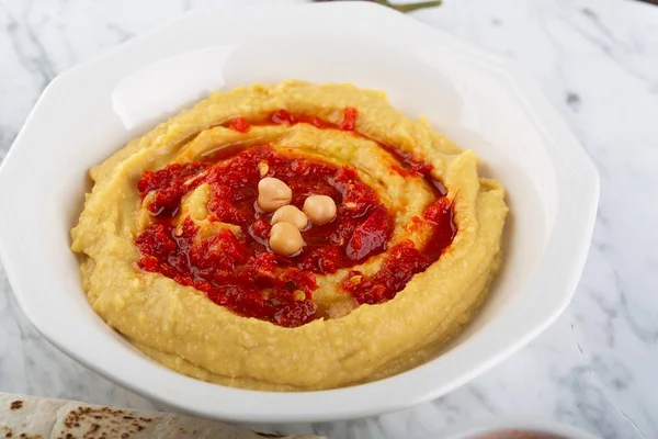 Hummus na talerzu. Danie z ciecierzycy przygotowane z sosem Harissa — Zdjęcie stockowe