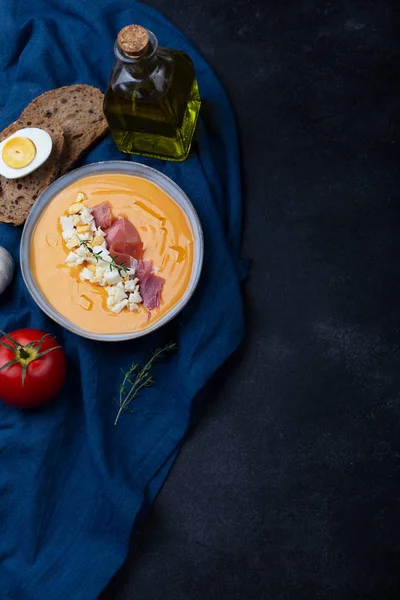 Salmorejo cordobes tipica zuppa di pomodoro spagnolo simile al gazpacho, condito con jamon serrano e uova, sfondo nero — Foto Stock