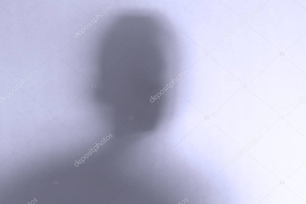 Defocused scary ghost face behind a white glass background