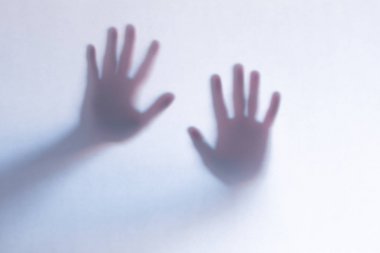 Beyaz cam arka plan arkasında korkunç hayalet eller defocused