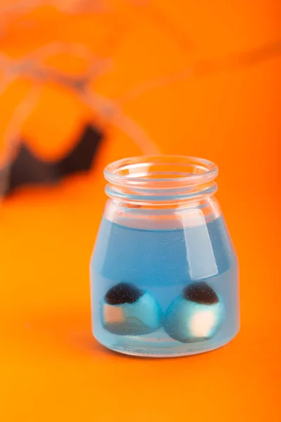 Koncepcja Halloween-dwa sztuczne oczy w niebieskim płynie na pomarańczowym tle — Zdjęcie stockowe