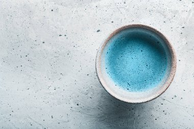 Mavi çay matcha bir kase ve kopyalama alanı ile beton yüzeyüzerinde kovalamak