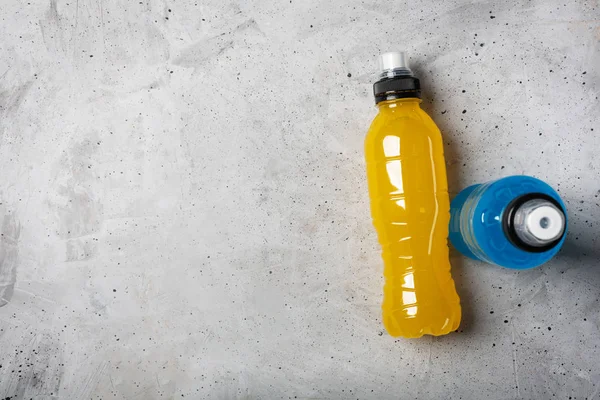 Isotonic energy drink. Bottles with blue and yellow transparent liquid, sport beverage on a concrete background — Stock Photo, Image