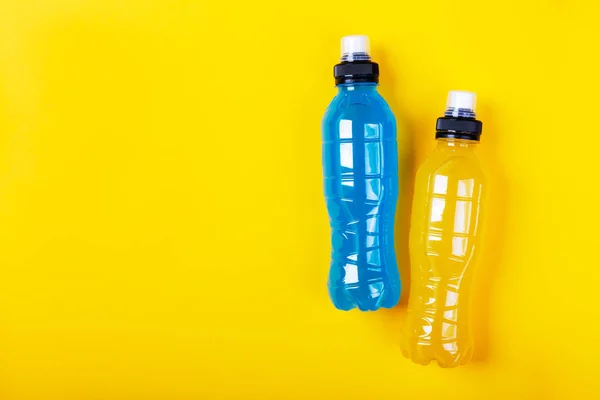 Bebida energética isotónica. Garrafas com líquido transparente azul e amarelo, bebida esportiva em um fundo colorido — Fotografia de Stock