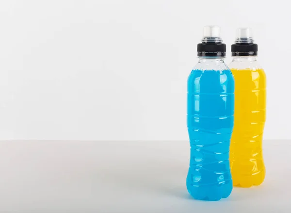 Isotonic energy drink. Bottles with blue and yellow transparent liquid, sport beverage on a white background — Stock Photo, Image